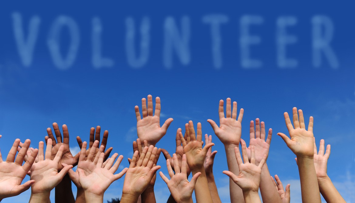 group of hands on a blue sky background with the word volunteer above them