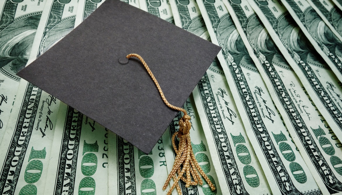 a graduation cap atop $100 bills