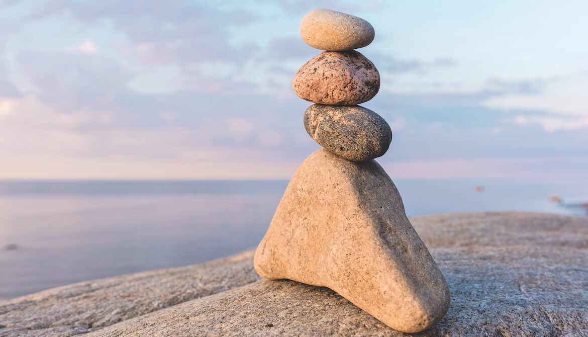 a cairn or stack or rocks on a beach with a beautiful blue sky