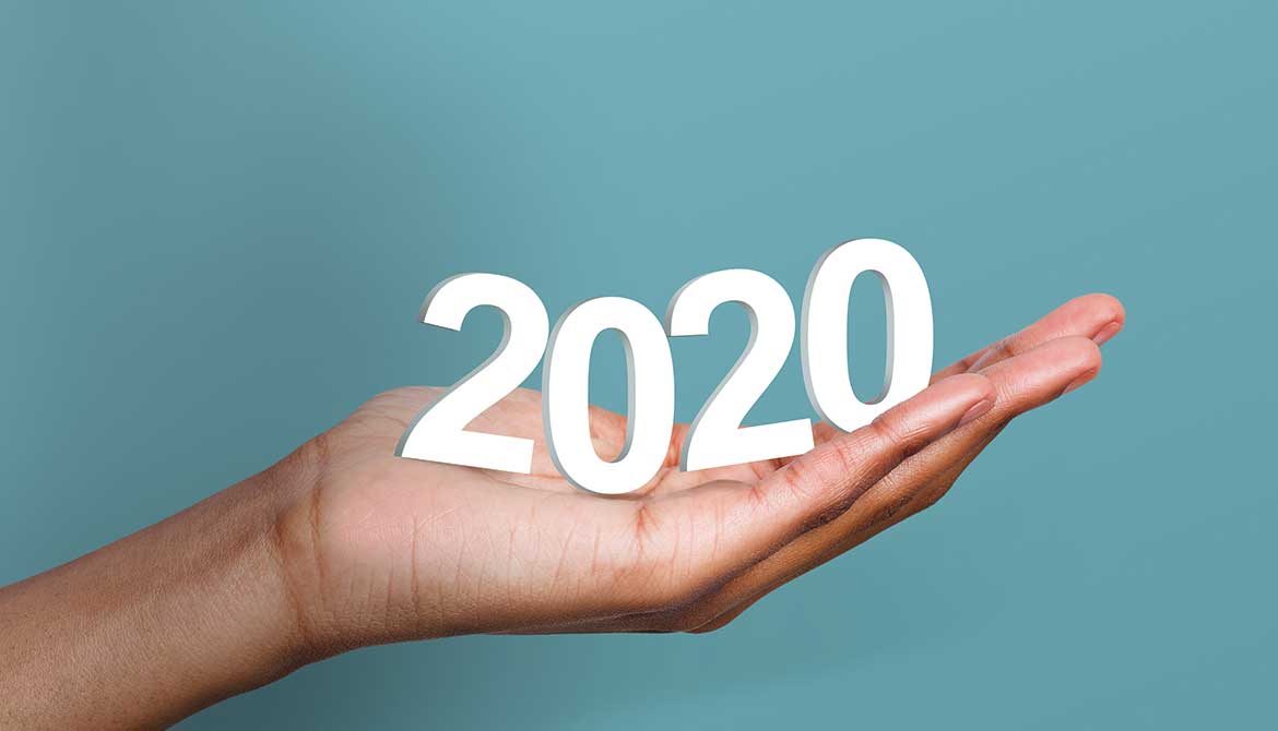 White 2020 year numbers in woman's hand on blue background