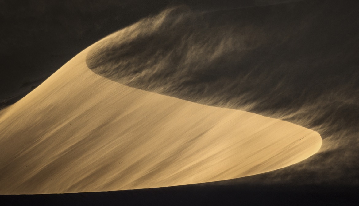 wind blowing across sand dunes
