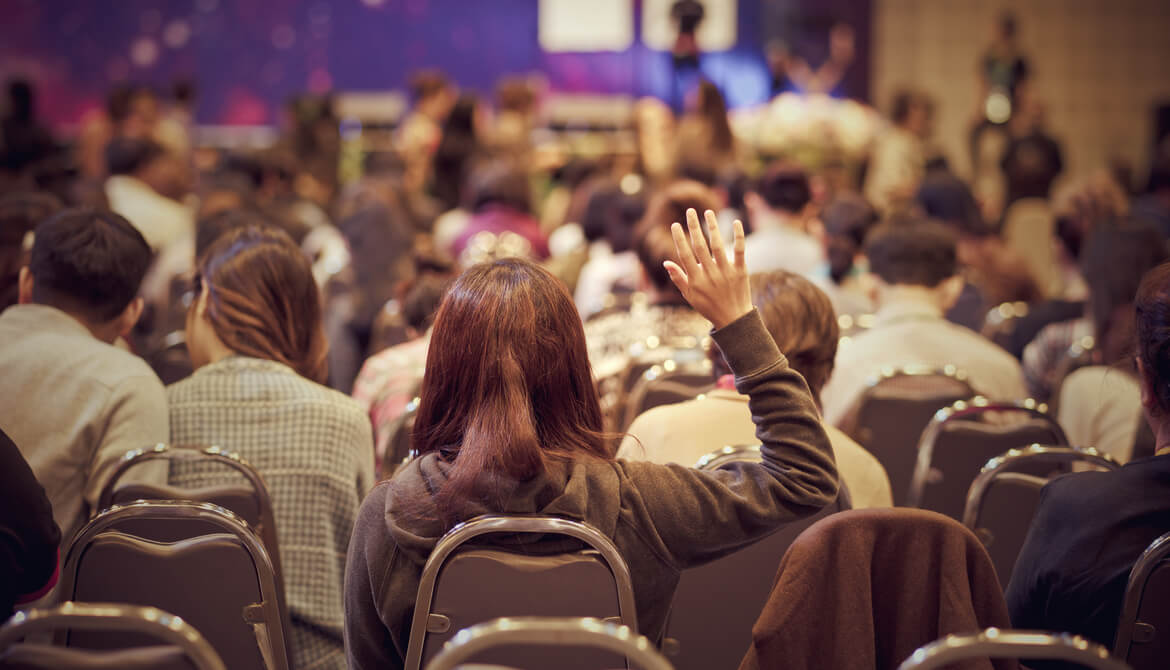 learner with hand up during conference session