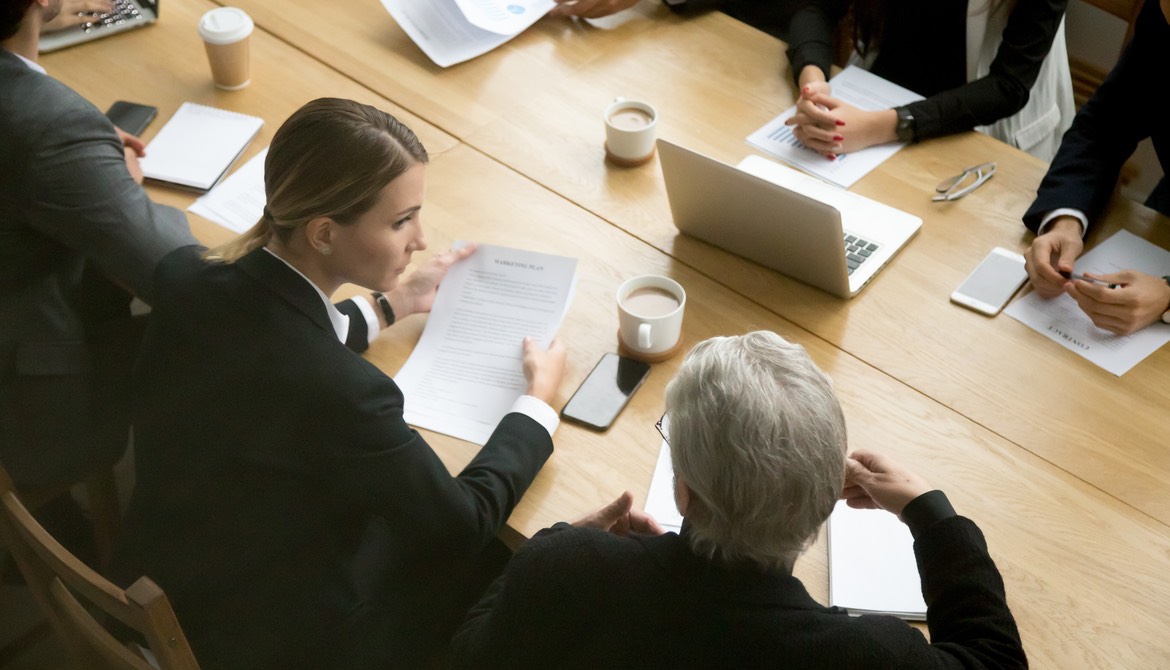 two groups of people on opposite sides of a table negotiating contract