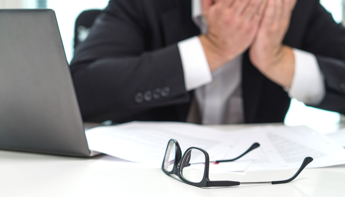 stressed out businessman holds his head in his hands at the office