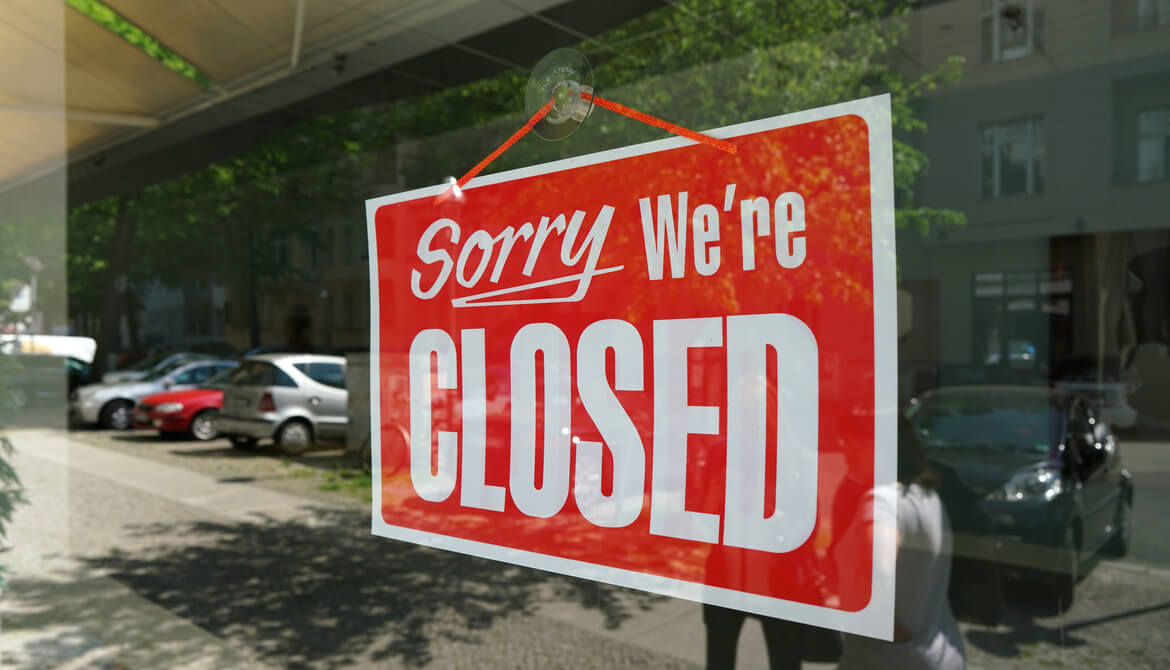 red sign in window of a business that says sorry we’re closed