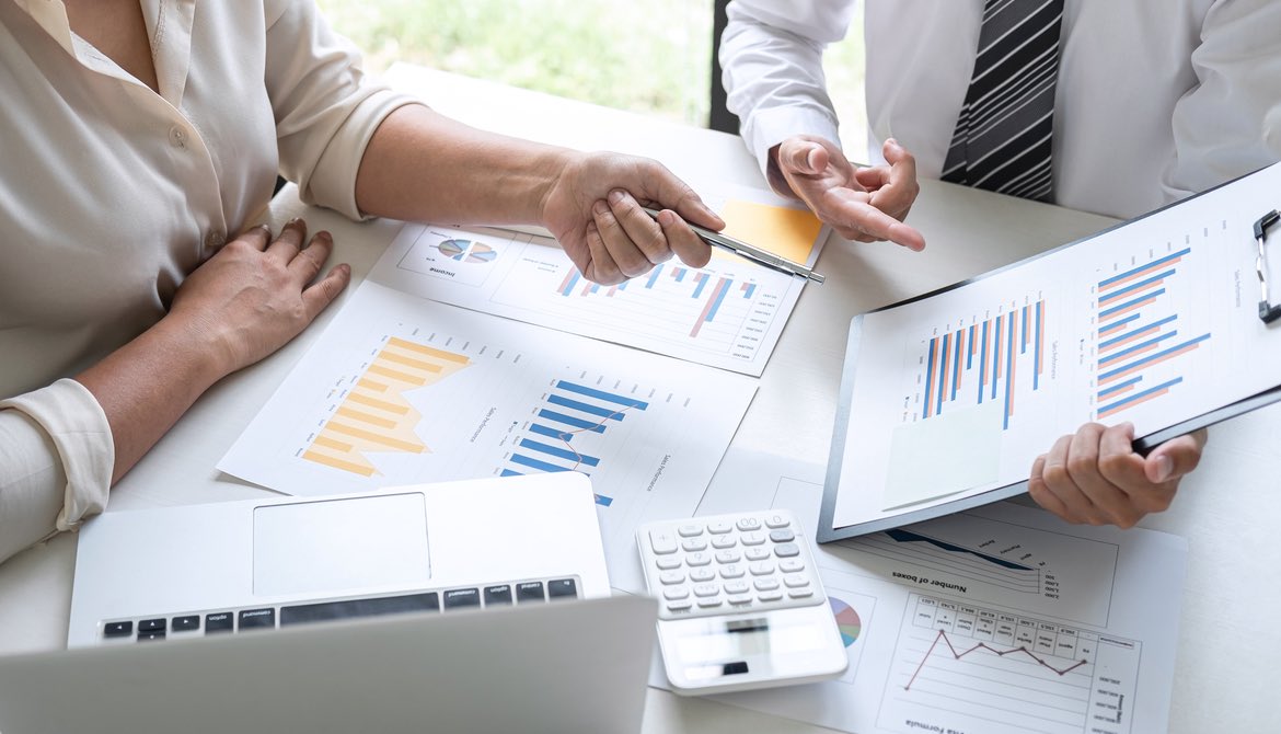 two executives at table with charts and graphs