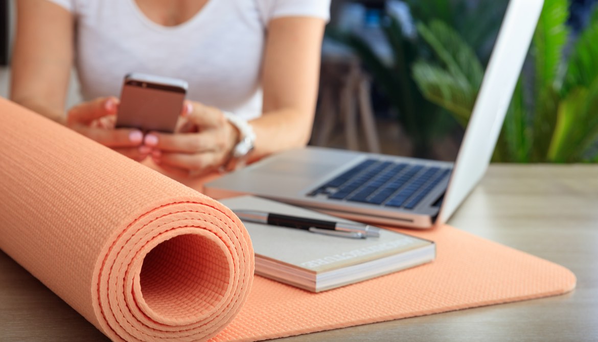 woman with laptop phone and yoga mat
