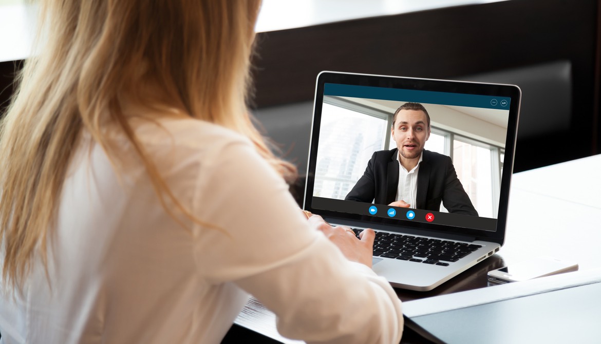 Woman using laptop to teleconference with a male executive