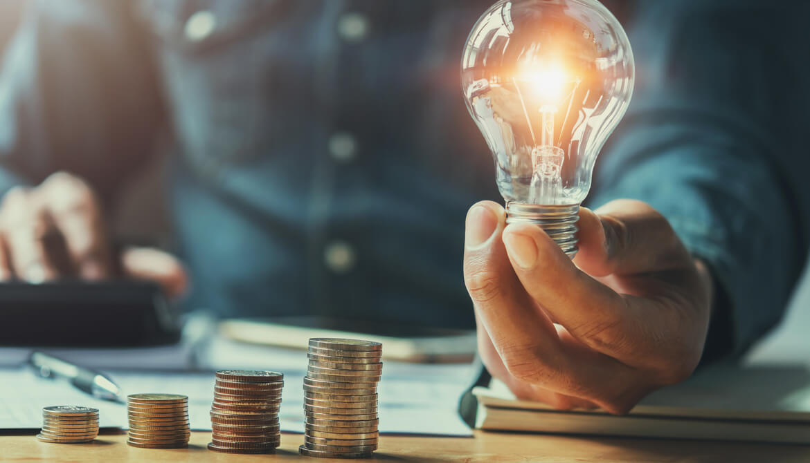 business man hand holding lightbulb with using calculator to calculate and money stack