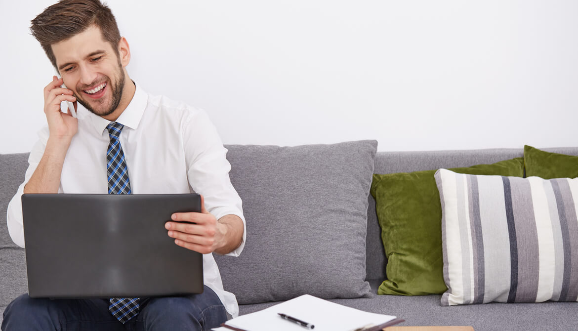 smiling young employee telecommuting with laptop