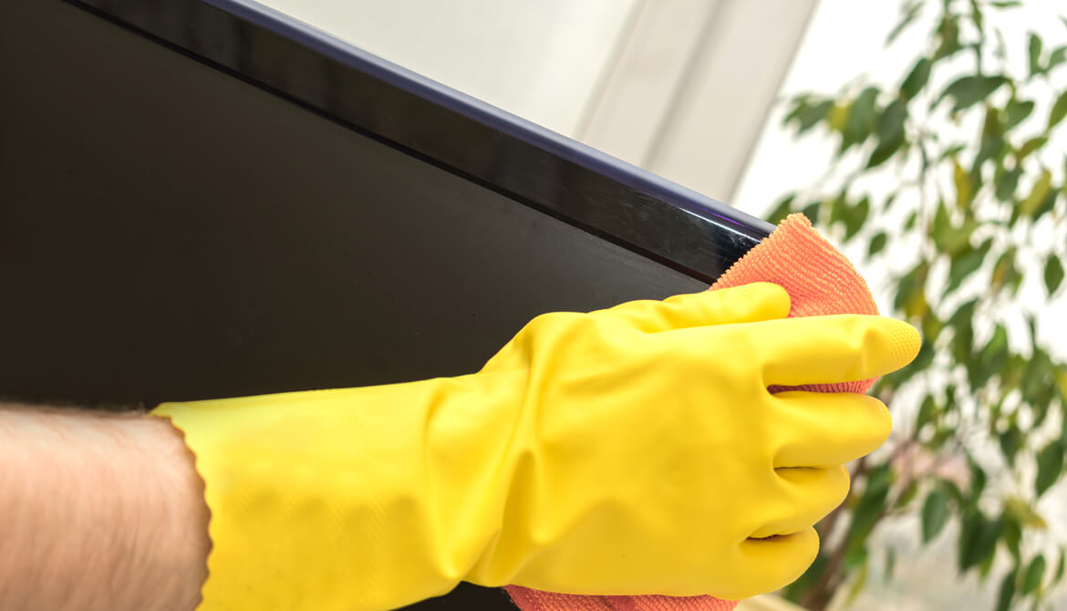 gloved hand cleaning computer screen