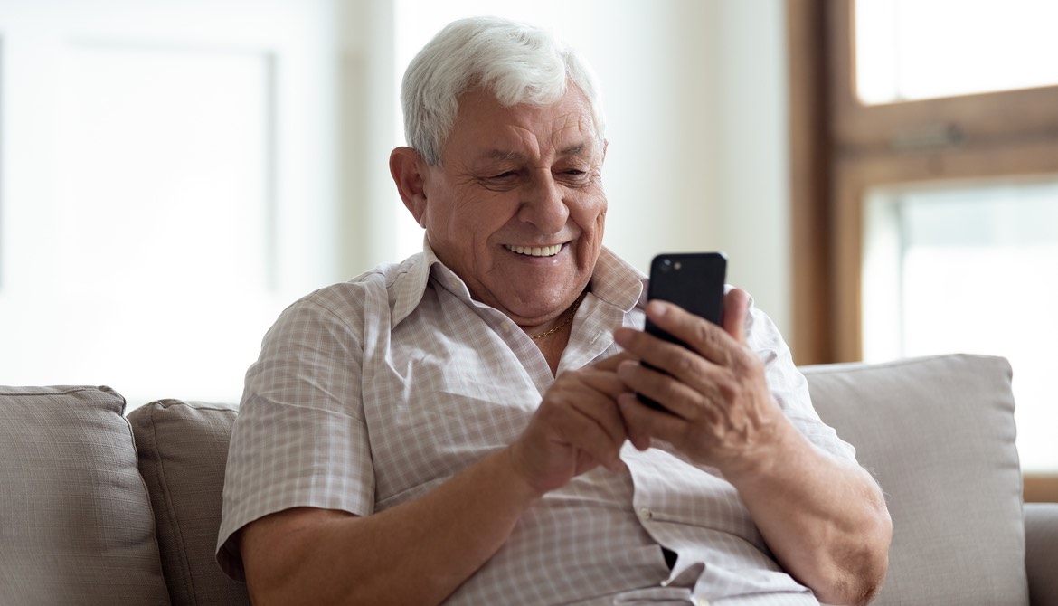 older man using smartphone on couch