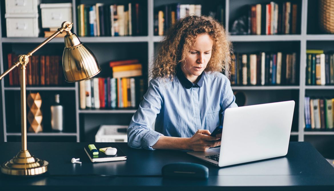 woman learning with laptop and phone in home office library office