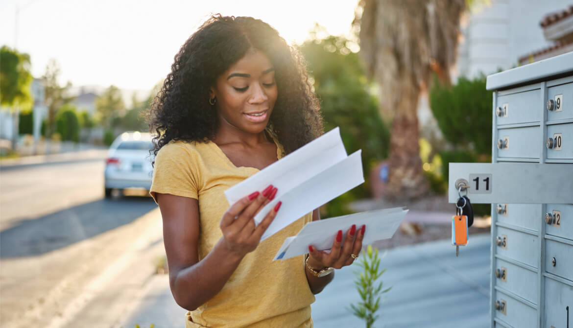 young African American woman checking her mail at bank of mailboxes