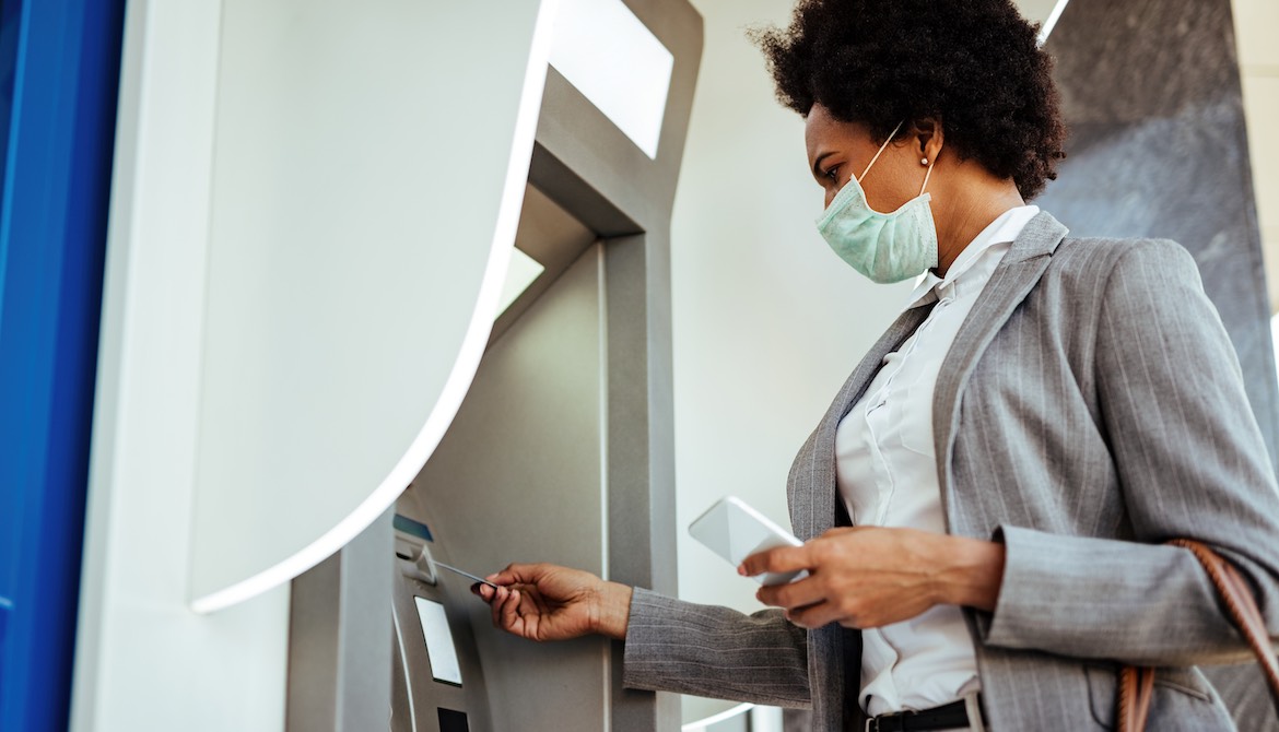 masked woman using atm during pandemic