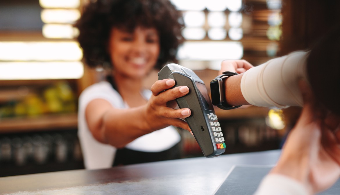 smiling clerk accepts contactless payment via apple watch