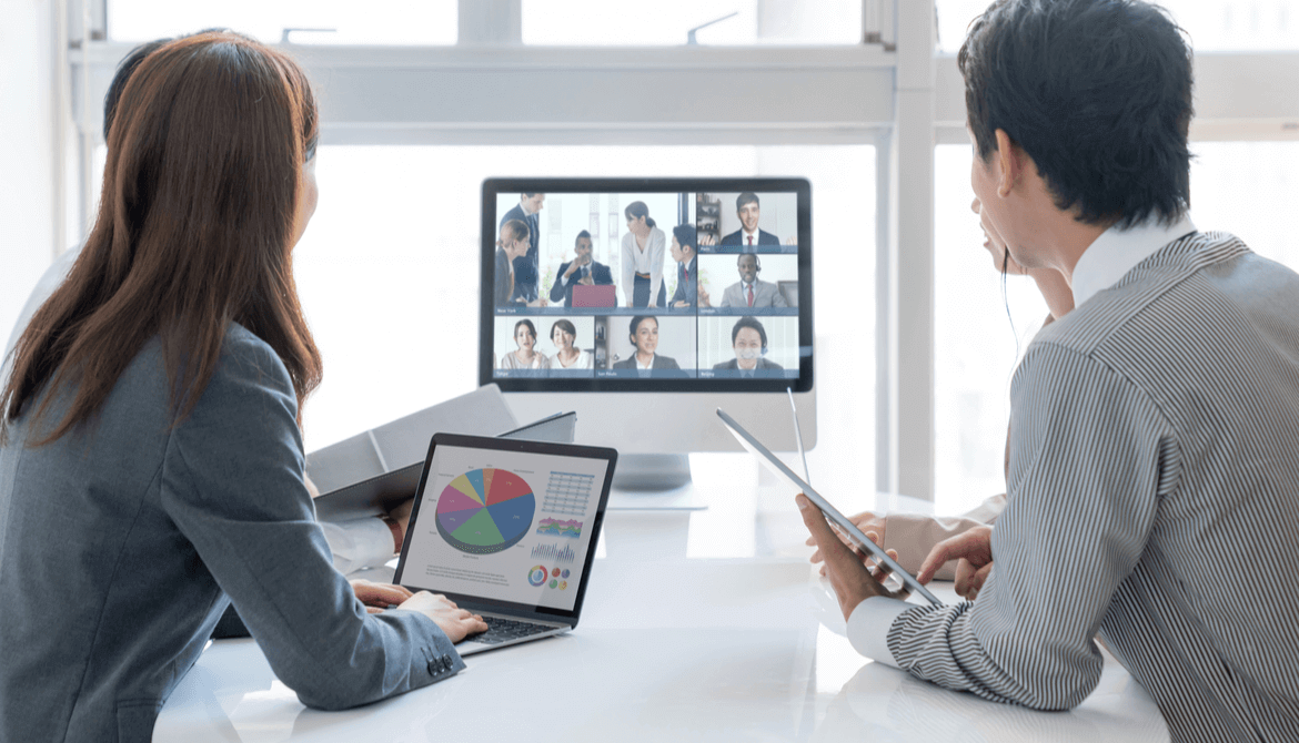 coworkers around table in office video conference with remote workers