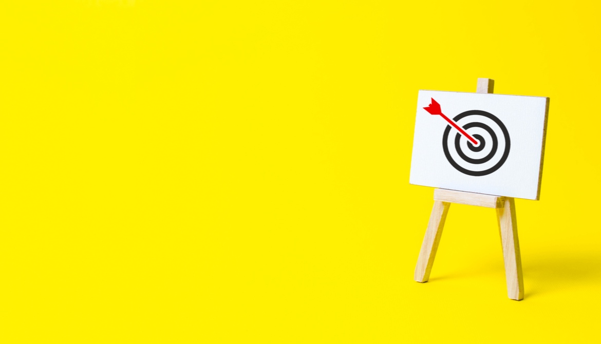 red arrow on target on easel on yellow background