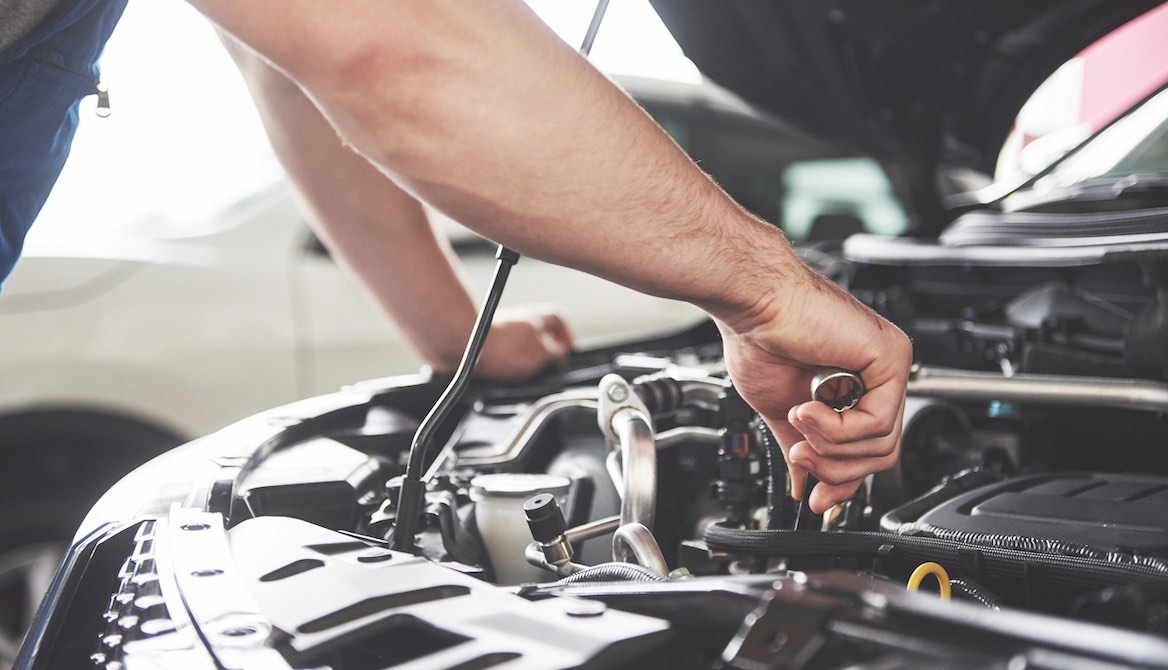 mechanic works on tuning up car engine