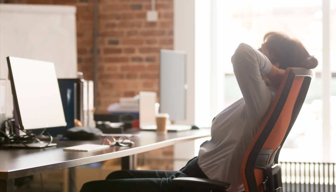 businesswoman leans back in office chair to destress and take mental break