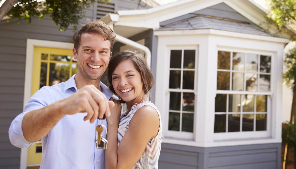 couple with keys standing outside new home