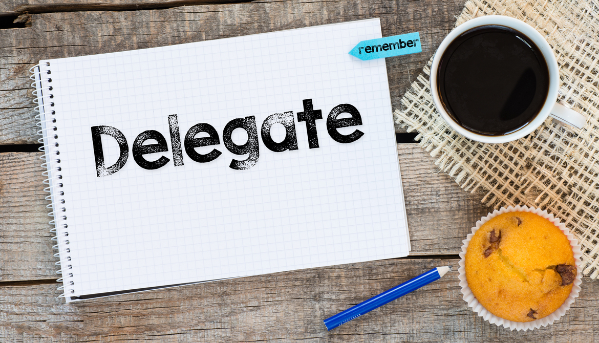 Notebook with delegate sign and sticker remember on wooden desk with cup of coffee and muffin