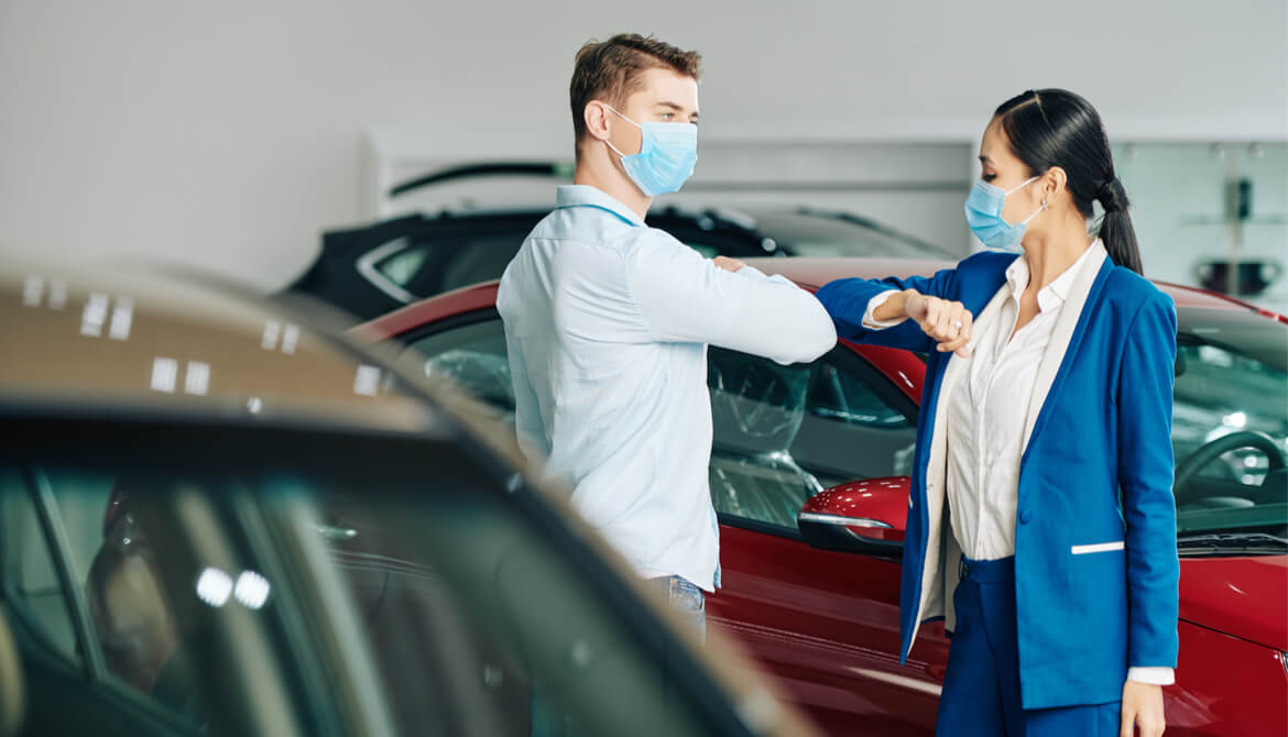 customer and car salesperson wearing masks bump elbows