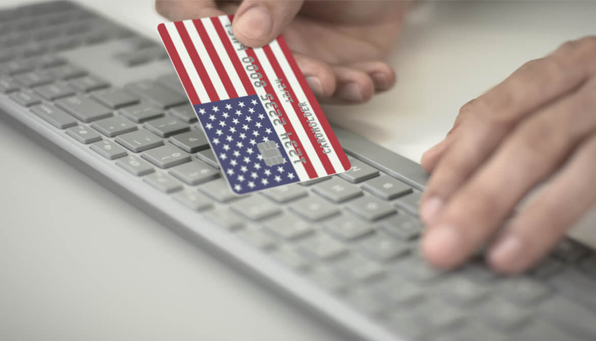 man making online payment using credit card with U.S. flag keyboard