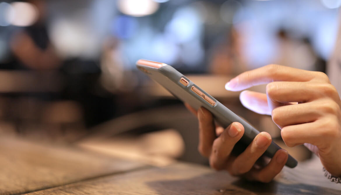 woman using a mobile smartphone on wooden table at night