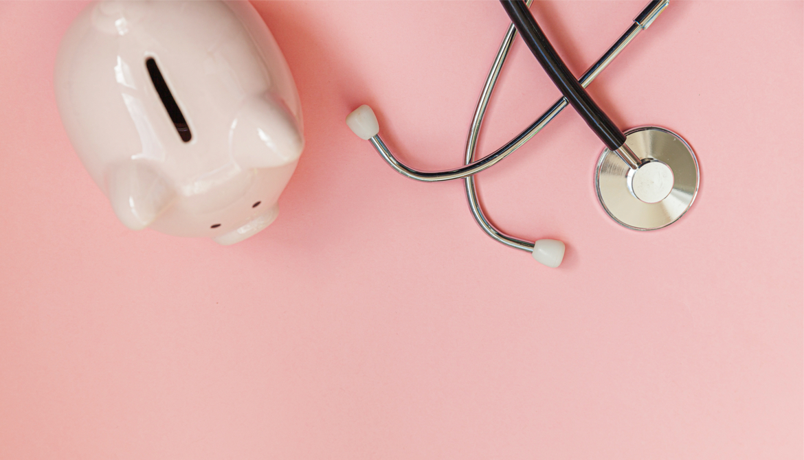 piggy bank and stethoscope on a pink background