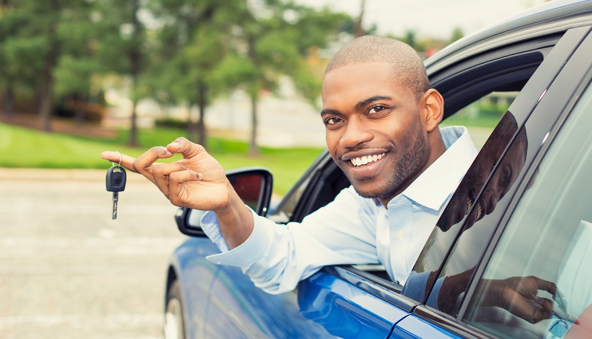 man in blue car leaning out window with key
