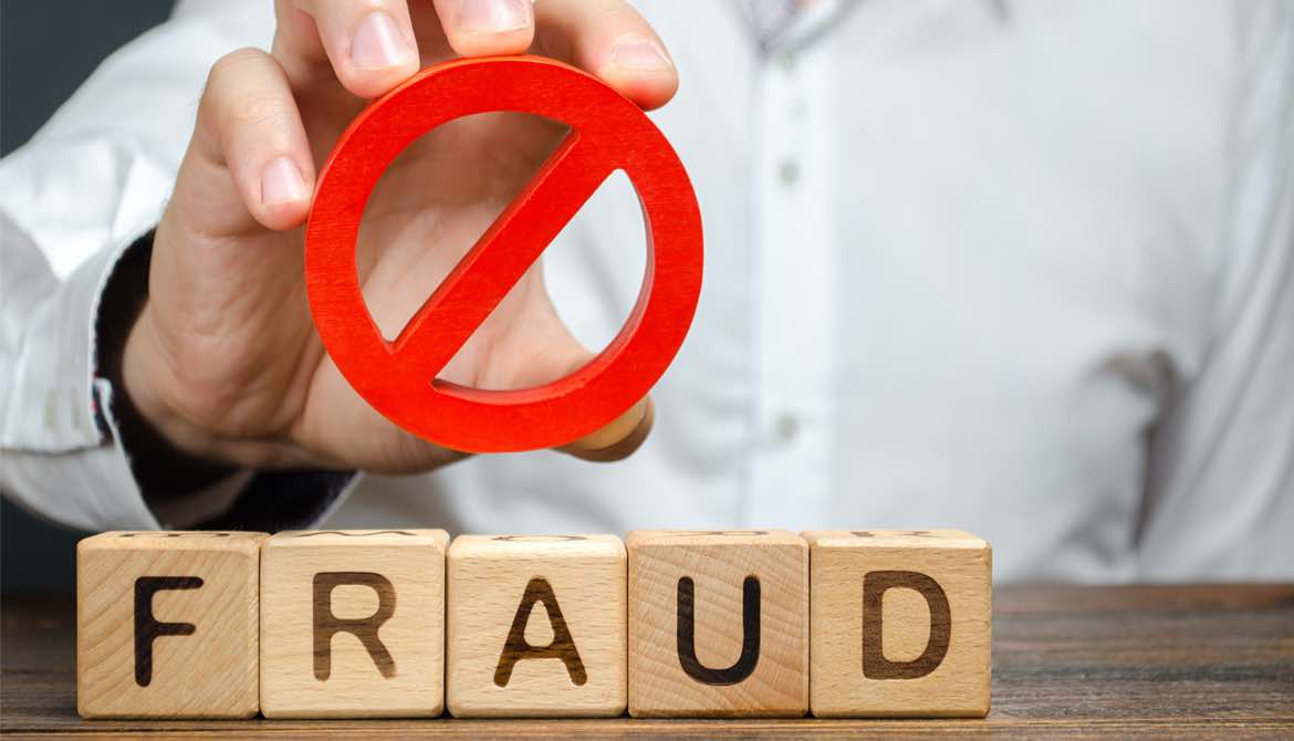 A man holds a red NO prohibition symbol over word fraud