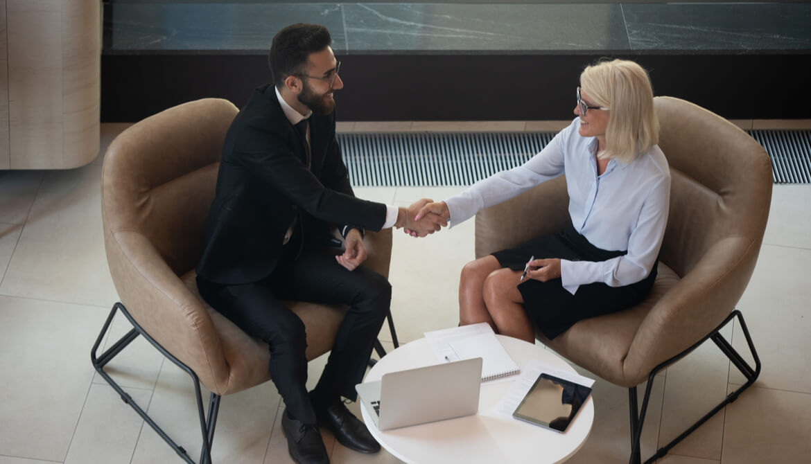 mature businesswoman shakes hands with younger businessman