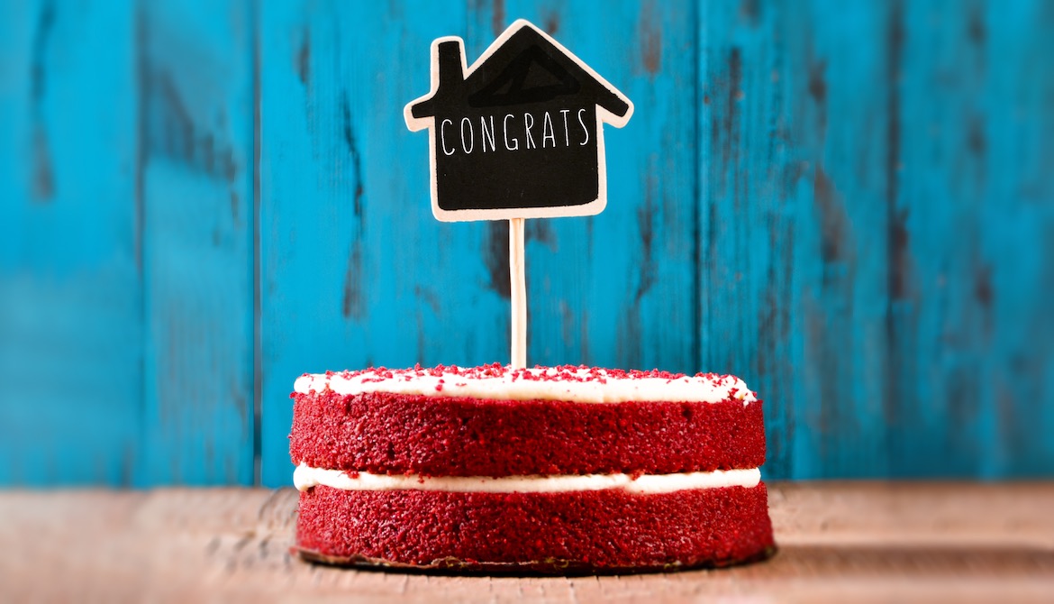 chalkboard congrats sign in shape of house stuck into a celebratory red velvet cake