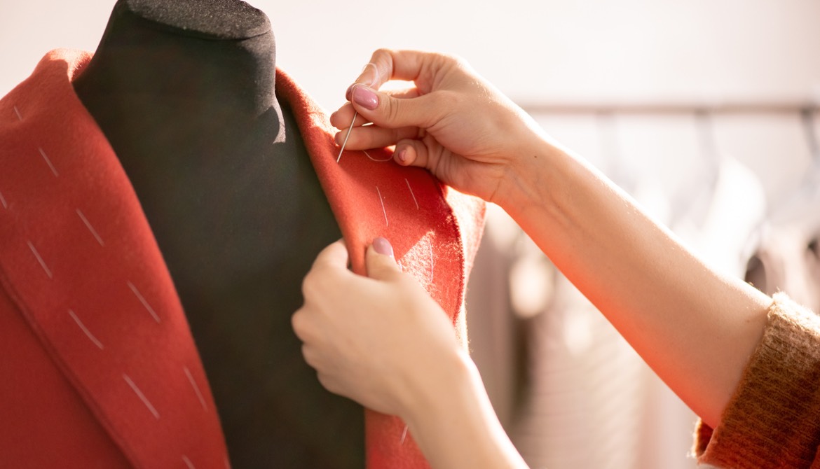 seamstress working on a coat on a mannequin