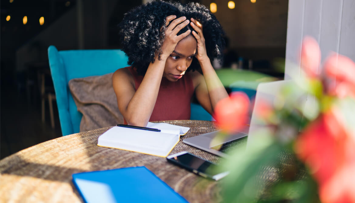 tired young Black woman studying online learning on laptop and notebook