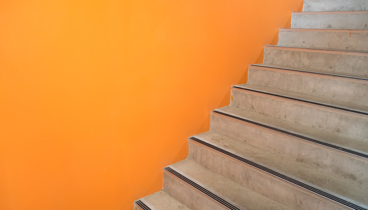 wooden staircase with an orange wall