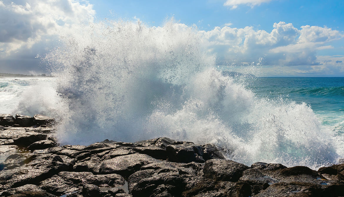 big wave crashing against rocks and spraying high into the air