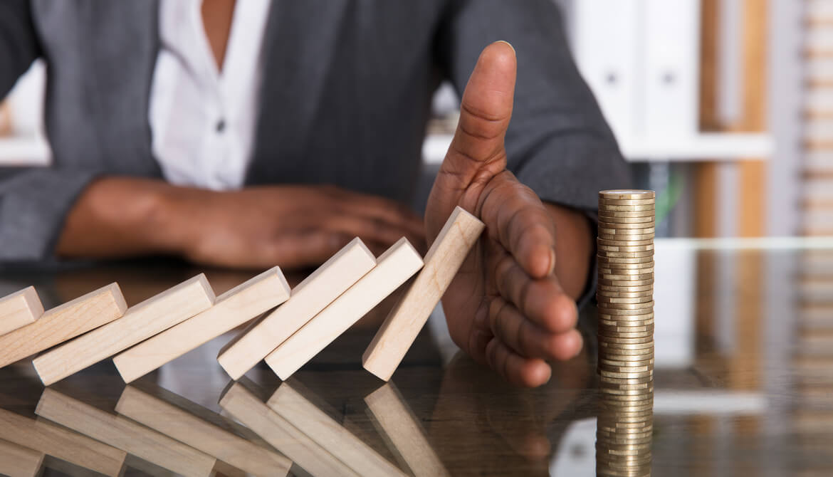 female executive using hand to stop domino-shaped blocks from falling in sequence