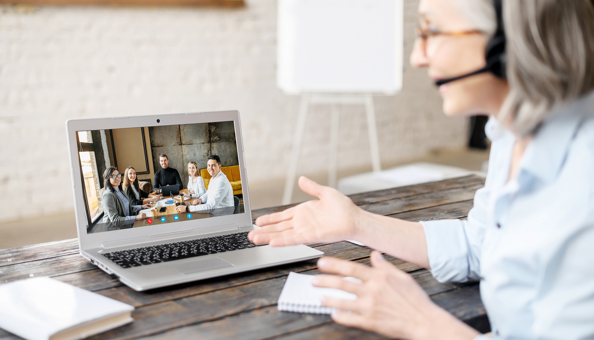senior executive uses laptop to videoconference with a team