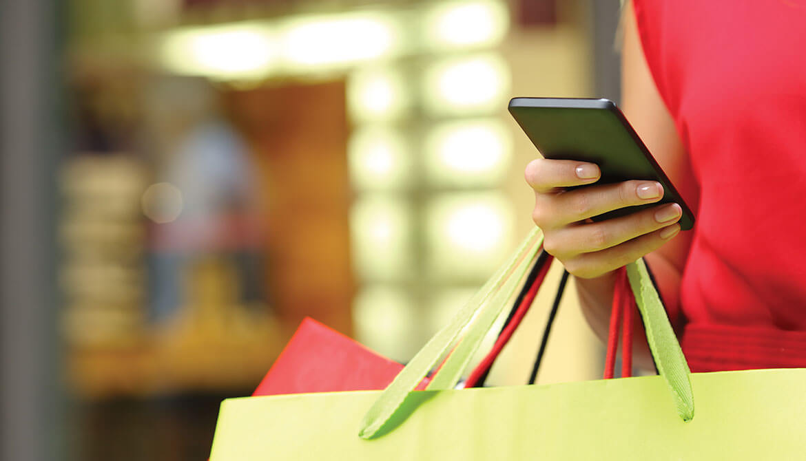 woman in red dress holding colorful shopping bags and a smartphone