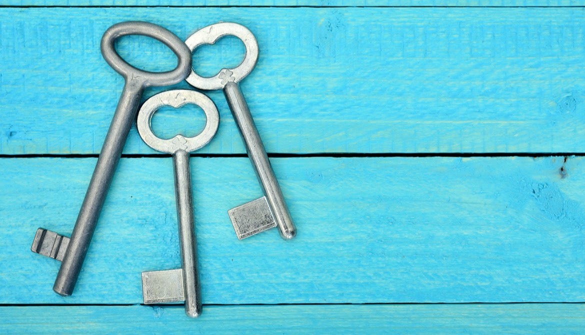 three old fashioned silver keys on a blue wooden background