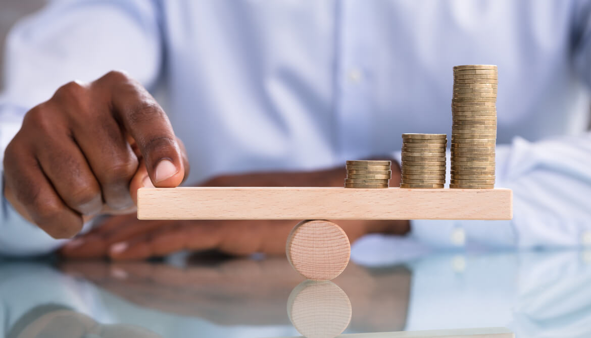 businessman balancing coin stack on wooden beam