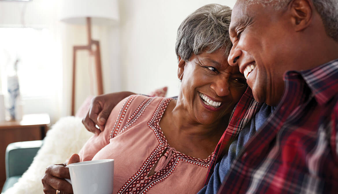 happy retired Black couple with arms around each other at home