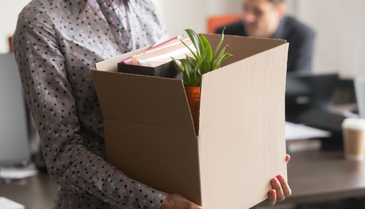 female employee carrying box of belongings as she prepares to leave office