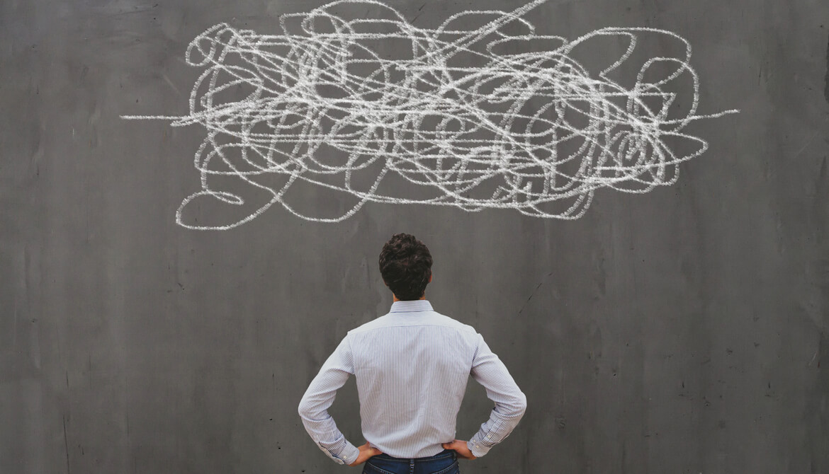 businessman studies squiggle of complexity drawn on chalkboard