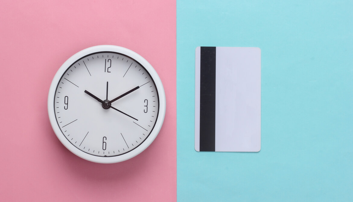 white clock and credit card on blue and pink