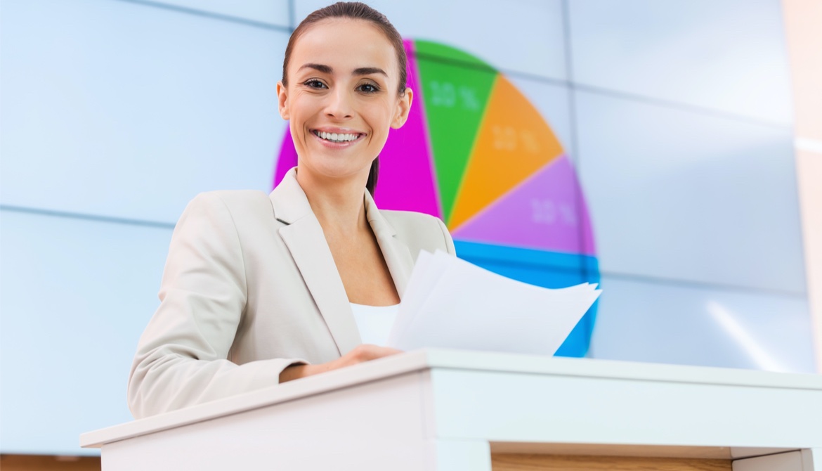 Confident young businesswoman standing at podium smiling before making presentation 
