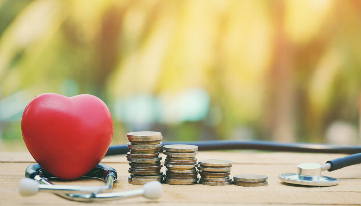 Red heart and stacks of coins surrounded by a stethoscope checking for financial wellness