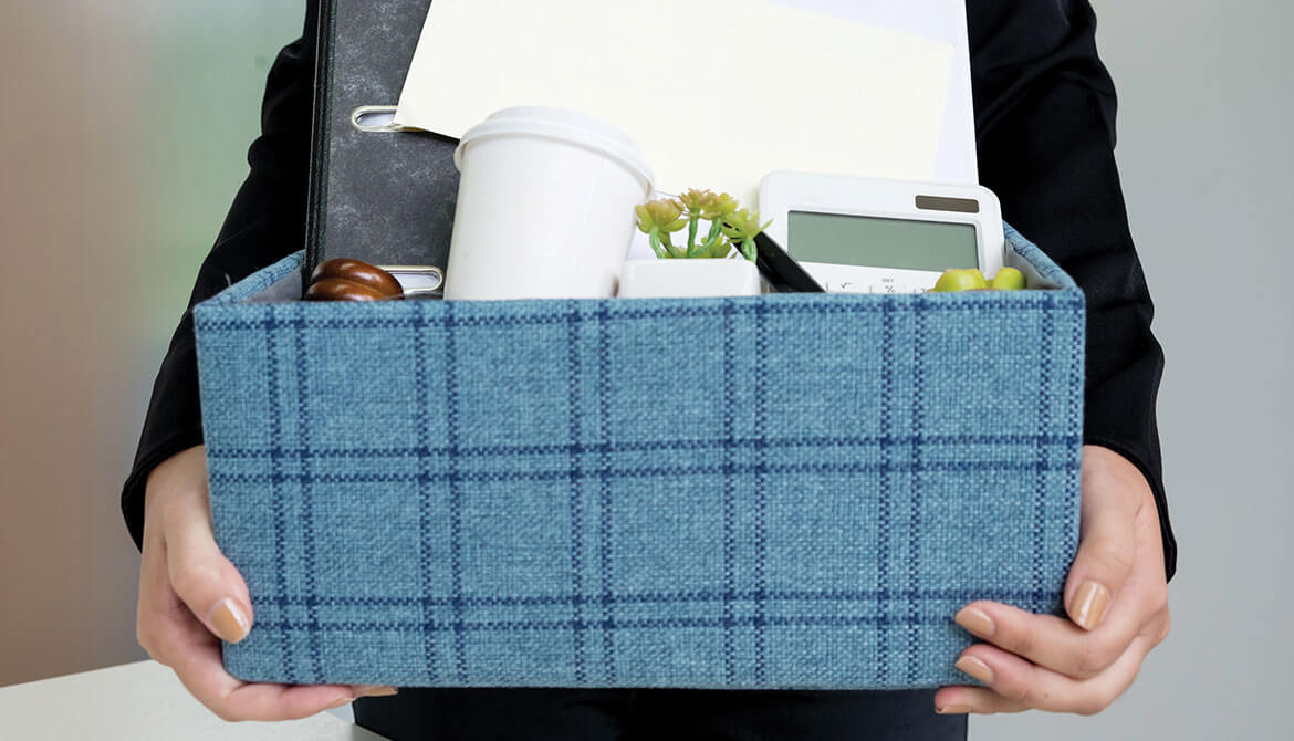 businesswoman carrying blue plaid box full of office belonings